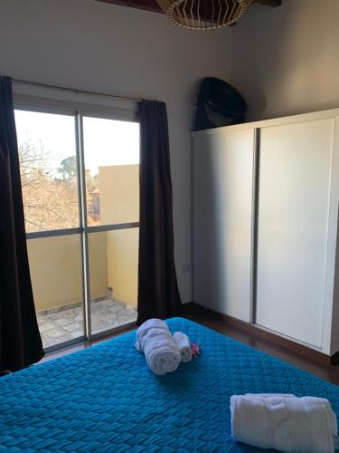a bedroom with a blue bed with a large window at Departamentos Monteolivos in Merlo