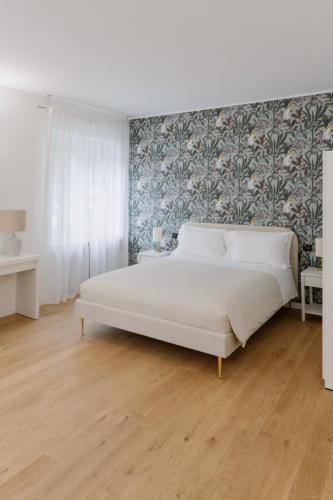 a bedroom with a large white bed with a floral wallpaper at Alatea Porta Nuova 20 in Verona