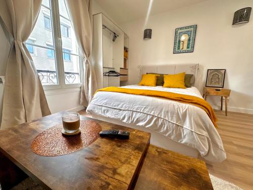 - une chambre avec un lit et une table avec une boisson dans l'établissement Magnifique Studio équipé à Clichy aux portes de Paris, à Clichy