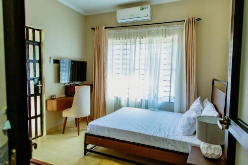 a bedroom with a bed and a window and a chair at Kwetu Maili6Homes 02 in Moshi