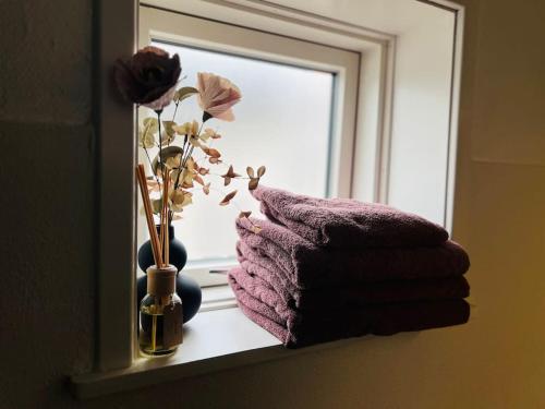 a window sill with a vase with flowers and a towel at Cozy Flats Silkeborg - S3 in Silkeborg