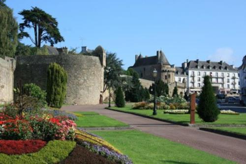 a garden with flowers and a castle in the background at Domaine des Lauriers 20 couchages in Languidic
