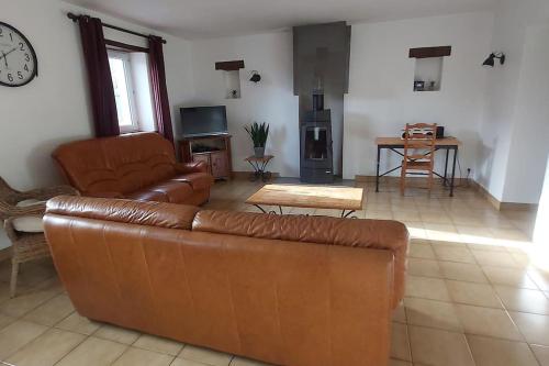 a living room with a leather couch and a table at Domaine des Lauriers 20 couchages in Languidic