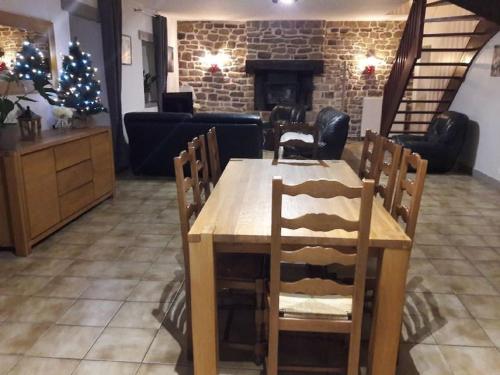 a table and chairs in a living room with a fireplace at Domaine des Lauriers 20 couchages in Languidic