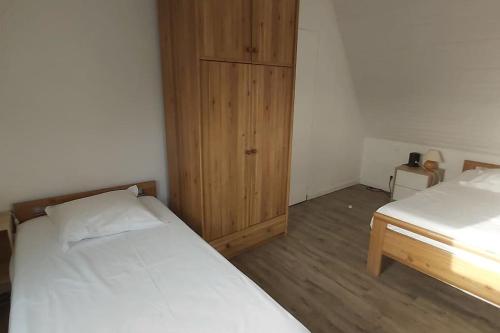 a bedroom with two beds and a wooden cabinet at Domaine des Lauriers 20 couchages in Languidic