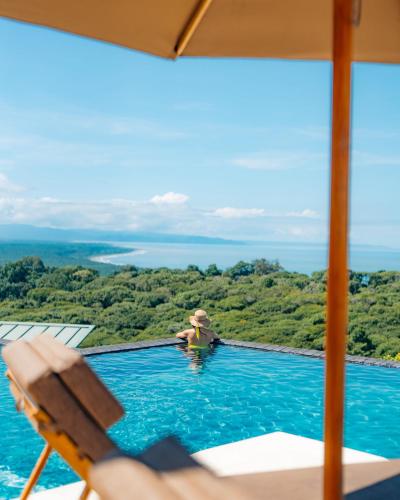 a woman in a swimming pool with a view of the ocean at Hotel Three Sixty - Adults Only in Ojochal