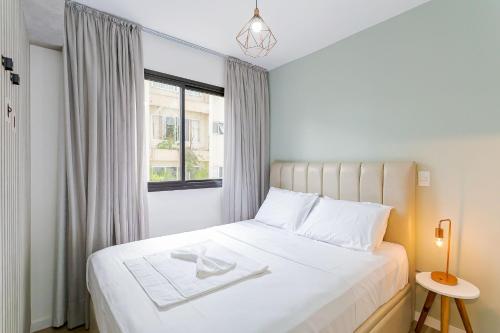 a bedroom with a white bed and a window at Edificio Easy Life | Mercês - Curitiba | Gonzaga Stays in Curitiba