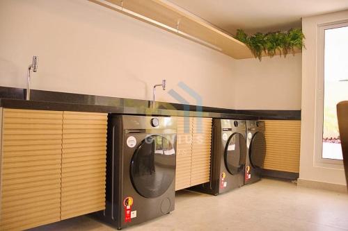 a row of washing machines in a laundry room at Puerto Ventura Cabo Branco Genius Flats in João Pessoa