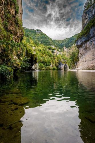 a river in a canyon with trees and rocks at La cabane au fond du jardin in Le Massegros