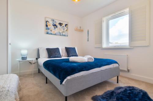 a bedroom with a bed with blue sheets and a window at Modern Spacious 3 Bedroom House in Canterbury with En Suite and Free Parking Perfect for Contractors & Families in Canterbury
