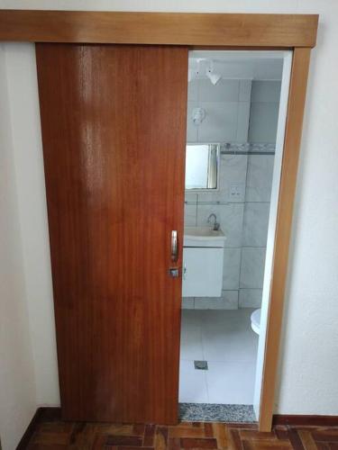 a wooden door leading to a bathroom with a toilet at Studio 330 - aconchegante, 500m da Feirinha do Alto, com Garagem e Wi-Fi 500MB in Teresópolis