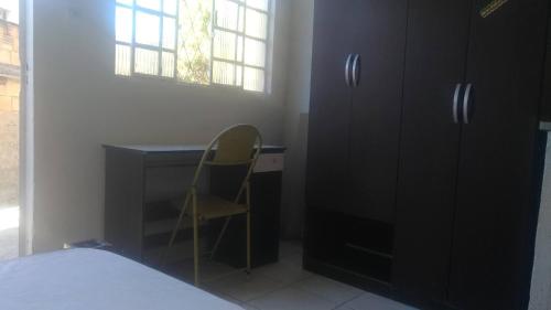 a bedroom with a desk and a chair next to a window at Kitnets in Contagem