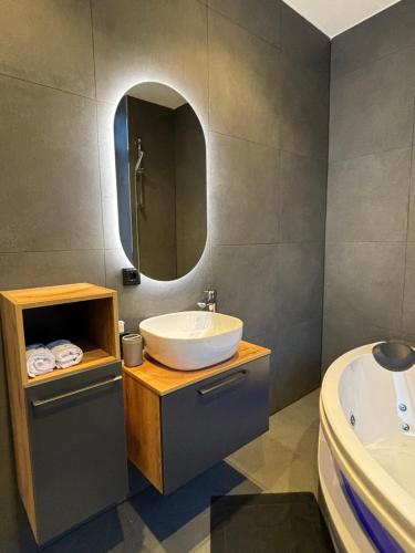 a bathroom with a sink and a mirror and a tub at Luxus Apartment mit Whirlpool in Kiel in Kiel