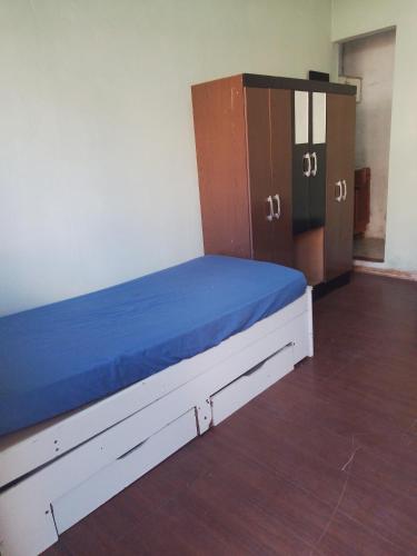 a room with a bed with blue sheets and wooden cabinets at Kitnets in Contagem