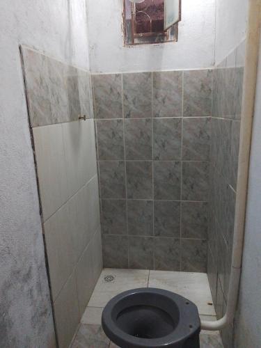 a bathroom with a toilet with a tiled wall at Kitnets in Contagem