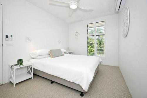 a white bedroom with a white bed and a window at Alex Heads, Prime Location, Stunning Views in Alexandra Headland