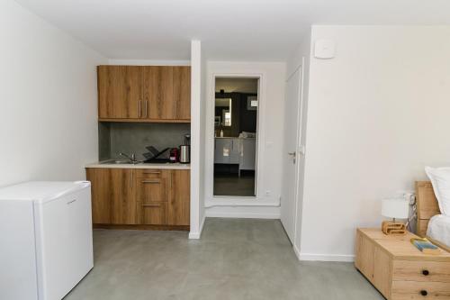 a kitchen with white walls and wooden cabinets at Aspa Luxury Garden Apartment in Vouliagmeni Center in Athens