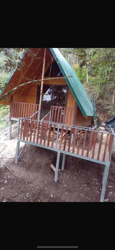 a wooden house with a green tarp on top of it at Cabañas Rabbits hole in Vara de Roble