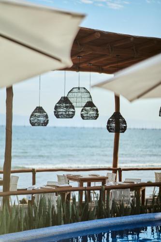 a pool with tables and chairs and the ocean at Hotel Ysuri Bucerias in Bucerías