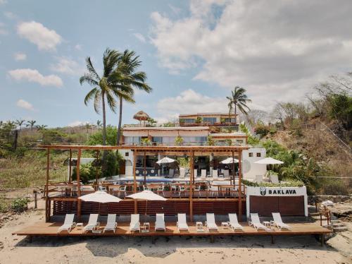 a resort on the beach with chairs and umbrellas at Hotel Ysuri Bucerias in Bucerías