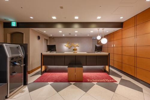 an office lobby with a desk and a red rug at Richmond Hotel Tokyo Mejiro in Tokyo
