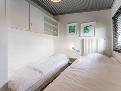 2 Betten in einem Zimmer mit weißen Wänden und einem Fenster in der Unterkunft Beachhouse II in Bergen aan Zee