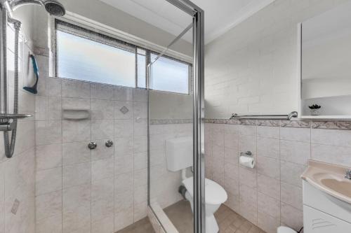 a bathroom with a shower and a toilet and a sink at Hydra 8 in Merimbula