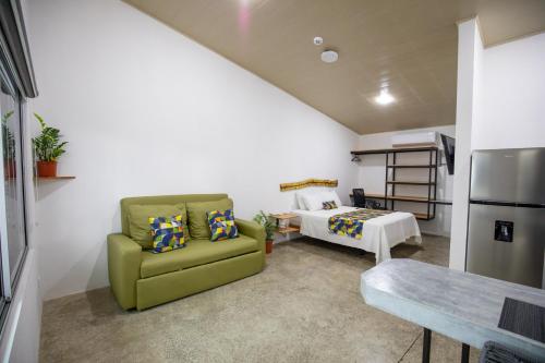 a living room with a green chair and a bed at Nomad Living CR Tárcoles in Tarcoles