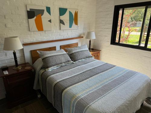 a bedroom with a bed and two lamps and a window at Hermosa casa con piscina climatizada todo el año en Bella Vista, Piriápolis in Bella Vista