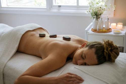 a woman laying on a bed with pills on her back at Bells at Killcare Boutique Hotel, Restaurant & Spa in Killcare