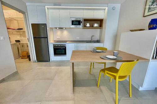 a kitchen with a wooden table and yellow chairs at Heifara city - Downtown Papeete in Papeete