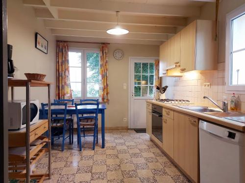 une cuisine avec une table et des chaises bleues. dans l'établissement Maison Nature avec Salle de Jeux, Jardin Clos, et Wi-Fi à Dampierre-sous-Brou - FR-1-581-19, à Dampierre-sous-Brou