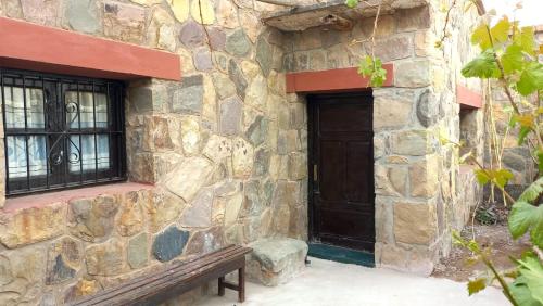 a stone building with a wooden door and a bench at La cabaña del carnavalito tilcara in Tilcara