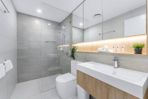 een badkamer met een wastafel, een toilet en een spiegel bij Coastal Chic 2 Bed Apt in Broadbeach in Gold Coast