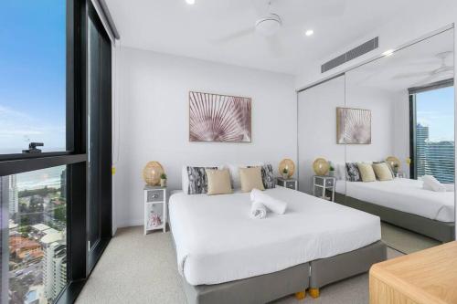 een witte slaapkamer met twee bedden en een raam bij Coastal Chic 2 Bed Apt in Broadbeach in Gold Coast