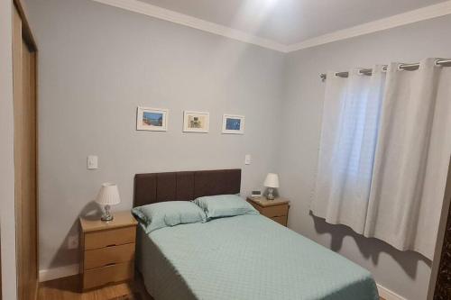 a bedroom with a bed and two lamps and a window at Assinatura Mensal in Bragança Paulista