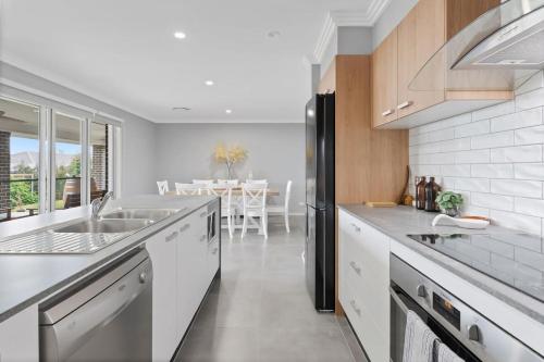 a kitchen with a sink and a refrigerator at Pineapple House Furry Friends Welcome in Cessnock