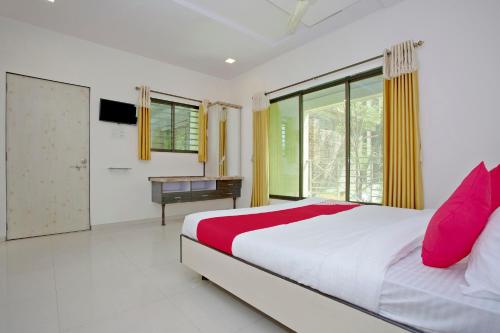 a bedroom with a bed and a desk and a window at Hotel O Capital O Sai Icon Residency in Titwala