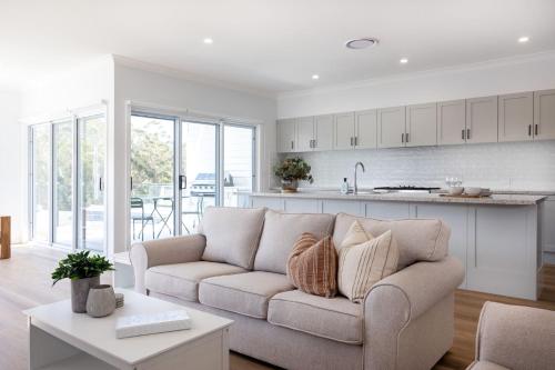 a living room with a couch and a kitchen at The White Pearl in Mollymook