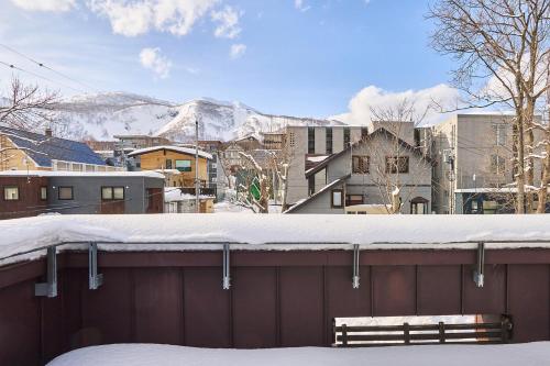a snow covered roof of a building with a bench at Niseko Central Houses and Apartments in Kutchan
