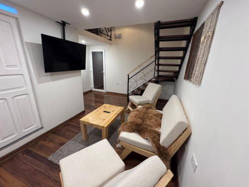 a living room with chairs and a tv and stairs at CASA CRISTOBAL Siete Cuartones in Cusco