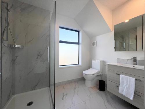 a bathroom with a shower and a toilet and a sink at Incredible luxury 3 floors Townhouse High Ceiling in Christchurch
