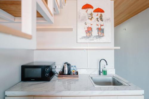 a kitchen with a sink and a microwave at Pondok Puspa Sumekar in Seminyak
