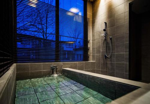 a bathroom with a shower and a tub with a window at Niseko Central Houses and Apartments in Kutchan