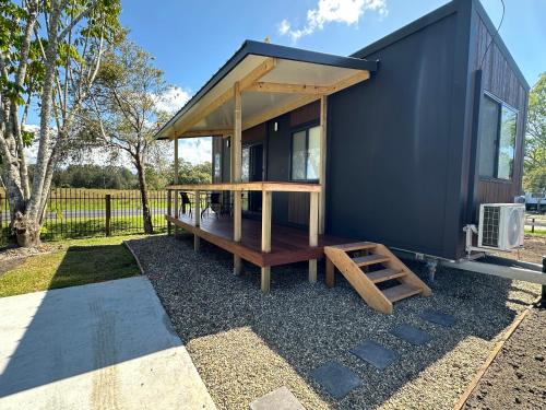 a black tiny house with a porch and a ladder at Bellinger River Tourist Park in Repton