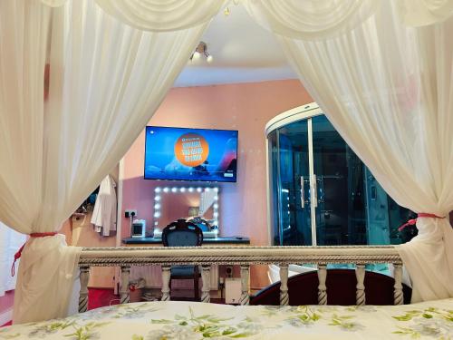 a bedroom with a bed with curtains and a tv at Annsborough House Castlewellan in Castlewellan