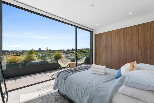 a bedroom with a bed and a large window at Coogee Beachside Penthouse 7 in Sydney