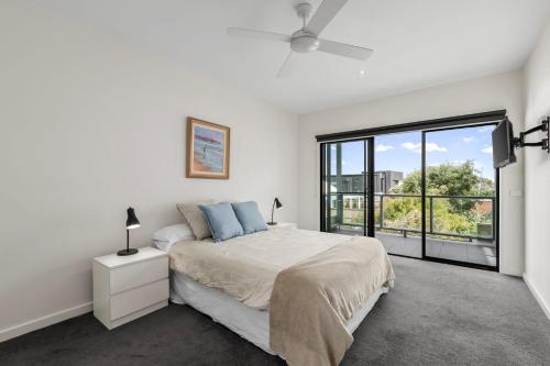 a white bedroom with a bed and a large window at Seaside Getaway in Point Lonsdale