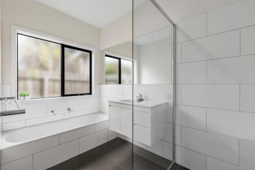 a white bathroom with a tub and a sink at Seaside Getaway in Point Lonsdale