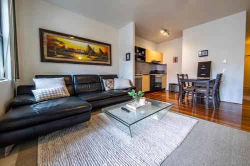 a living room with a black leather couch and a table at Teneriffe Executive Suites in Brisbane